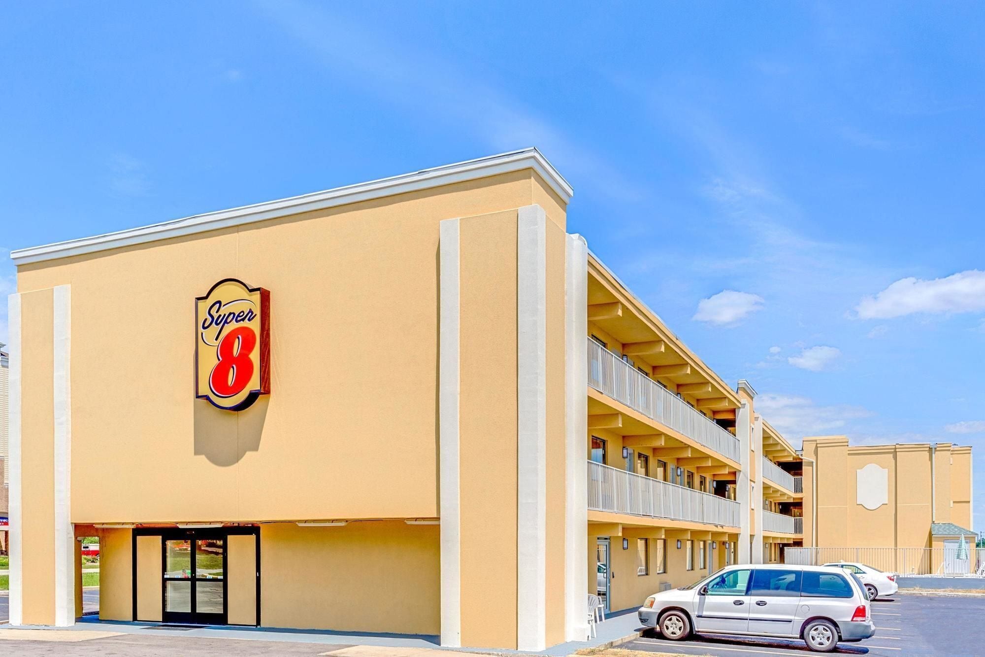 A Super 8 hotel with a two-story structure, a prominent 'Super 8' sign, and a parking lot with cars.