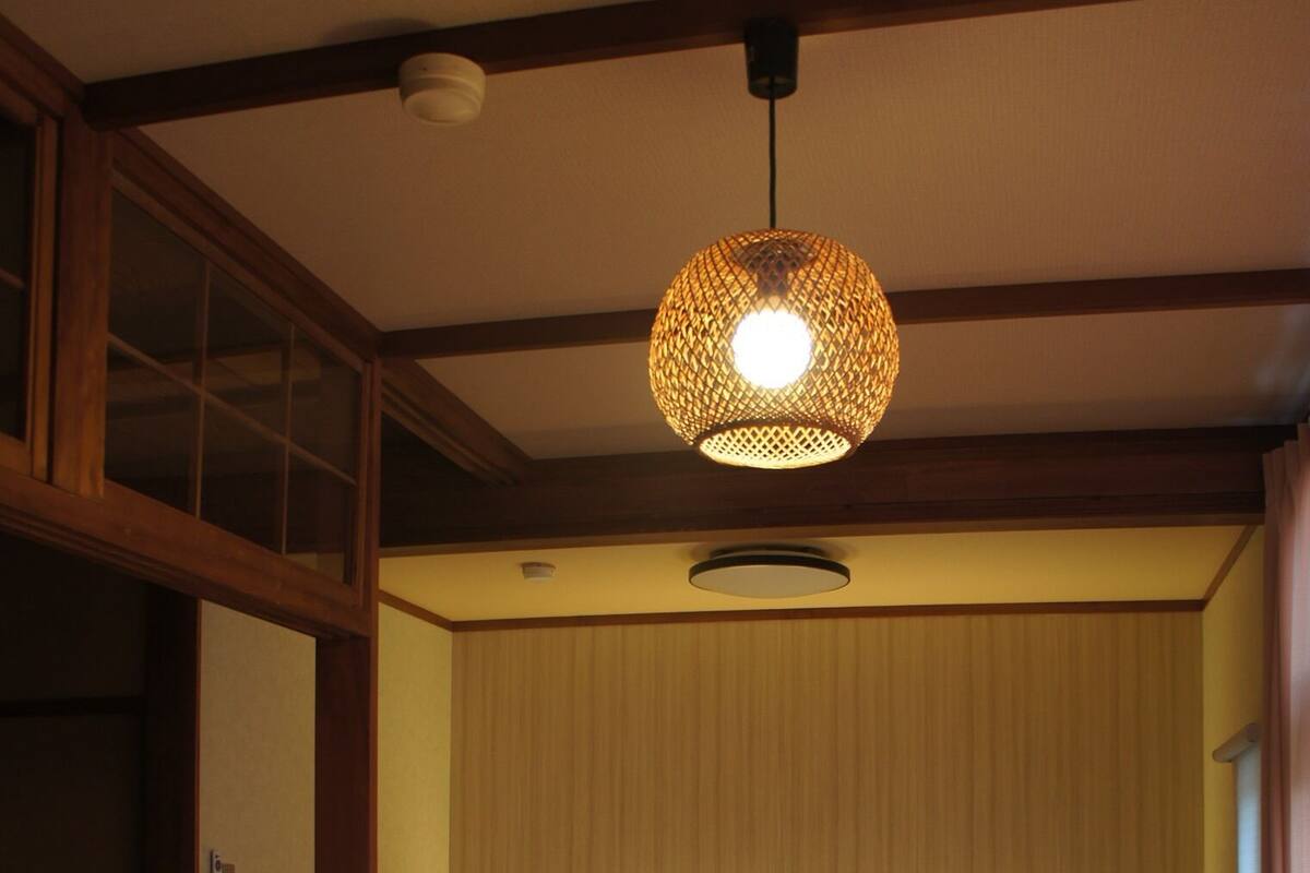 A traditional Japanese-style room with two beds, a tatami mat, and a hanging lamp.