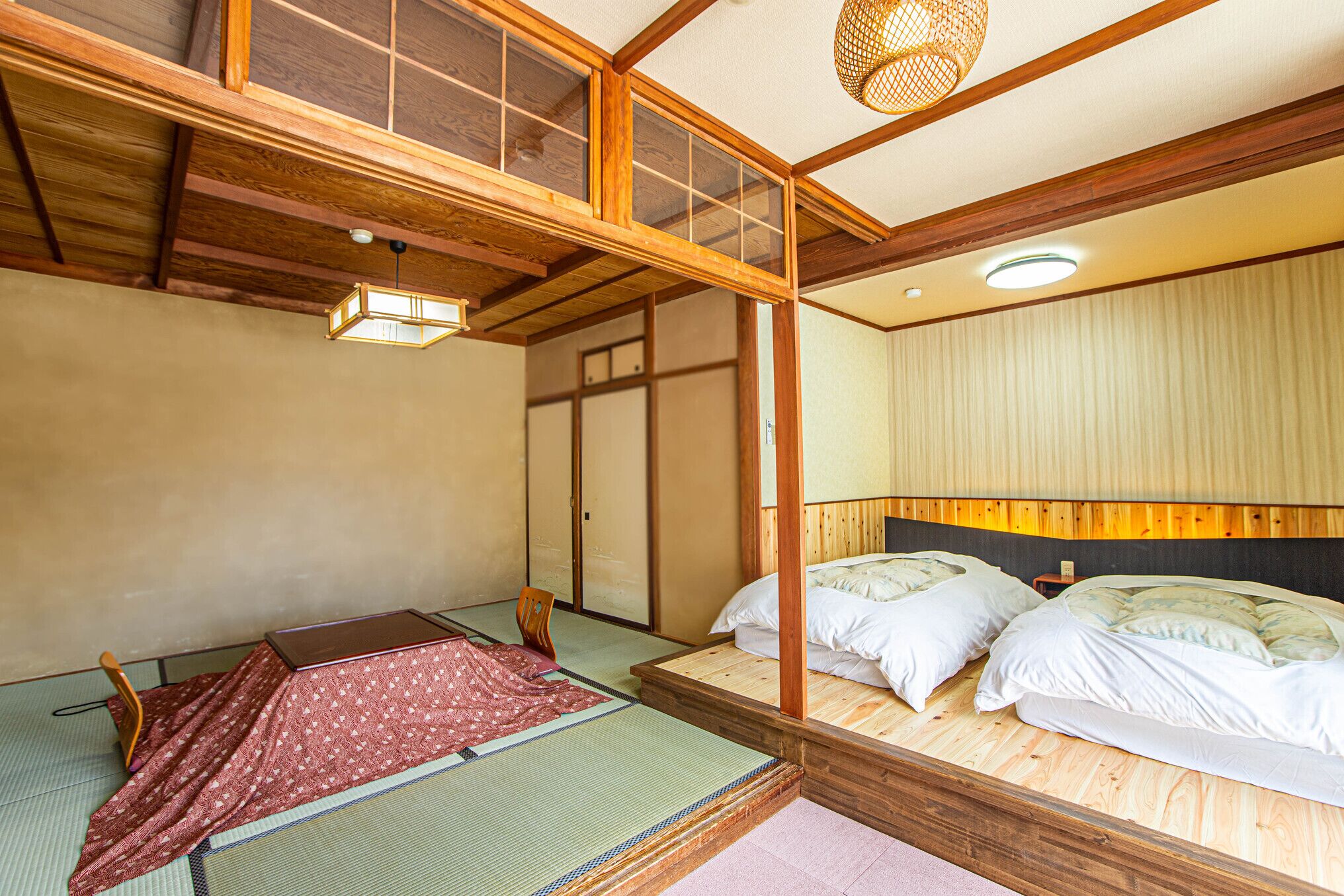 Una habitación japonesa tradicional con suelo de tatami, una cama de madera baja, un futón y una puerta corredera.