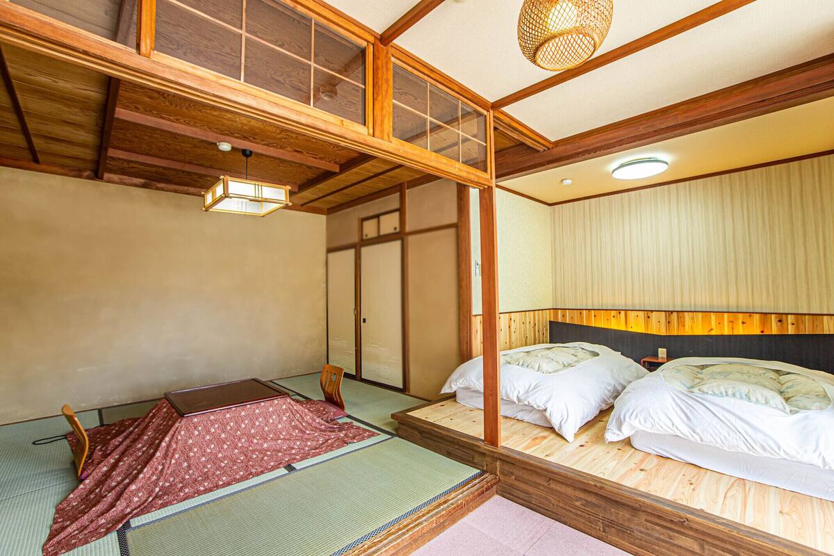 A traditional Japanese room with tatami flooring, a low wooden bed, a futon, and a sliding door.