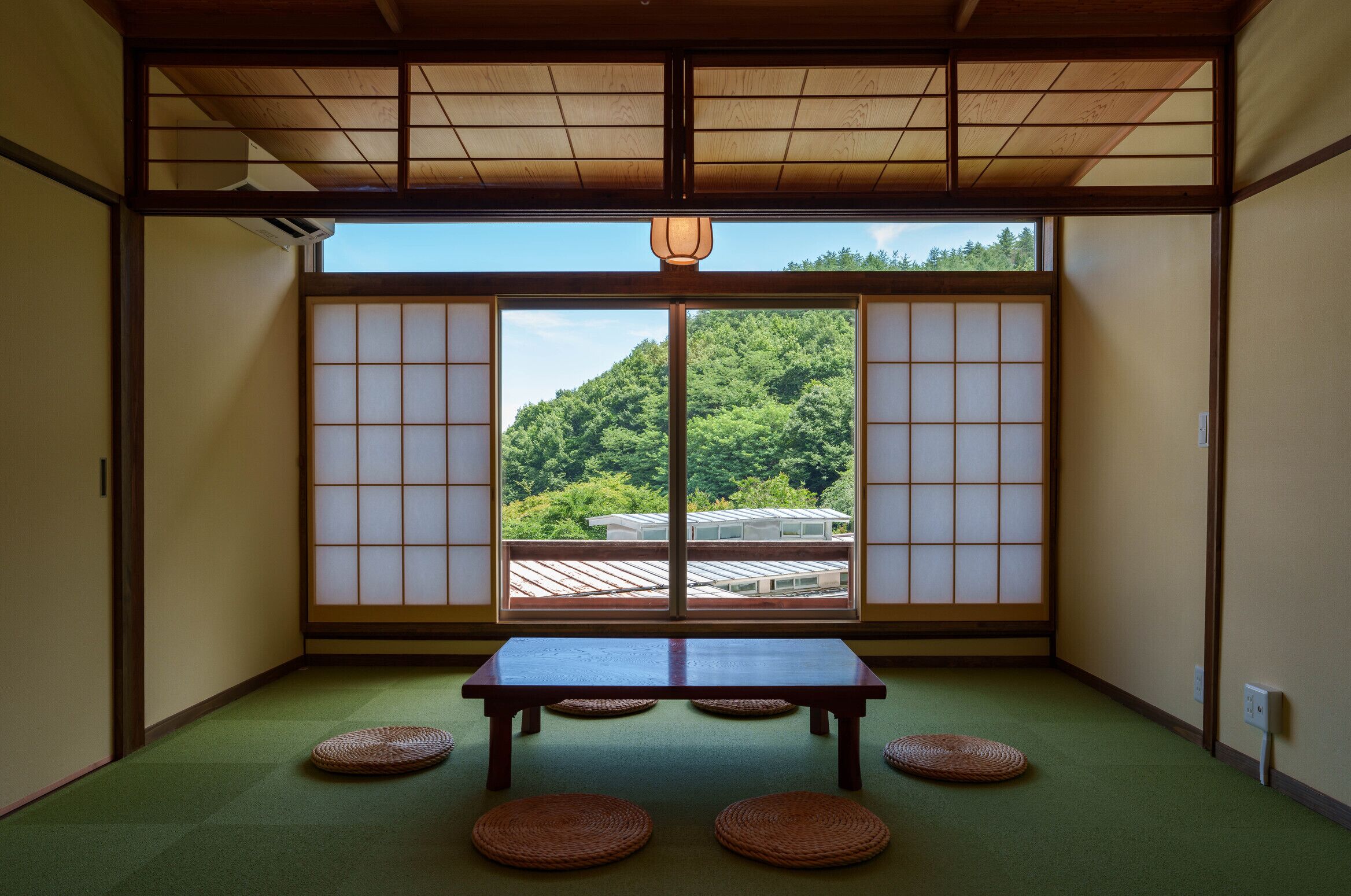 Una habitación japonesa tradicional con suelo de tatami, una mesa baja y puertas correderas shoji.