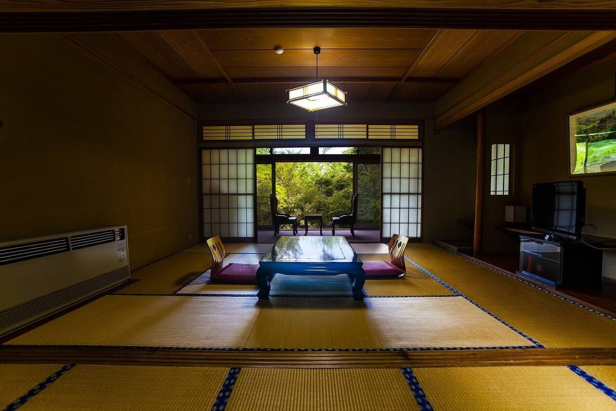A traditional Japanese room with tatami flooring, a low table, and sliding doors.