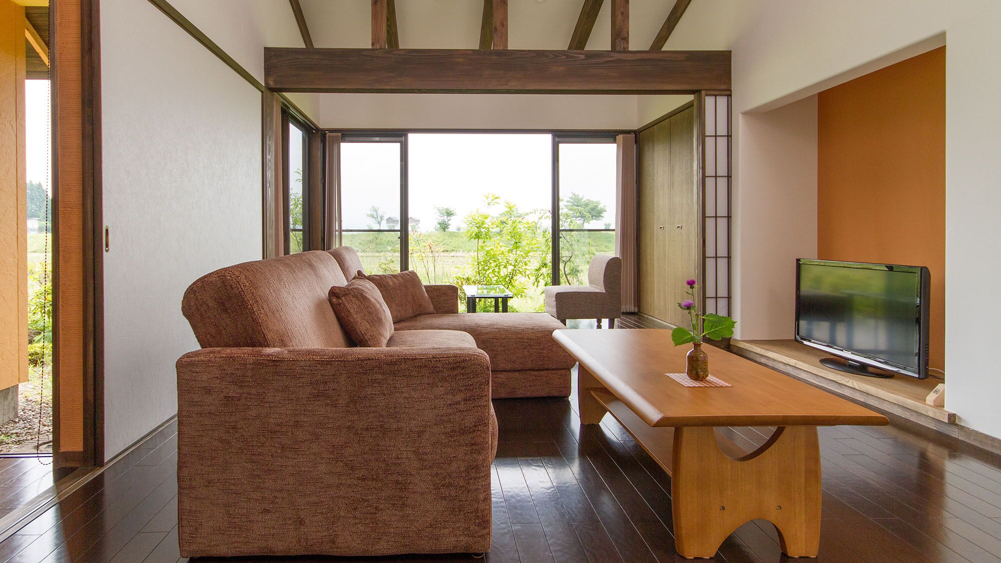 Een moderne woonkamer met een zithoek, een houten salontafel en een televisie.