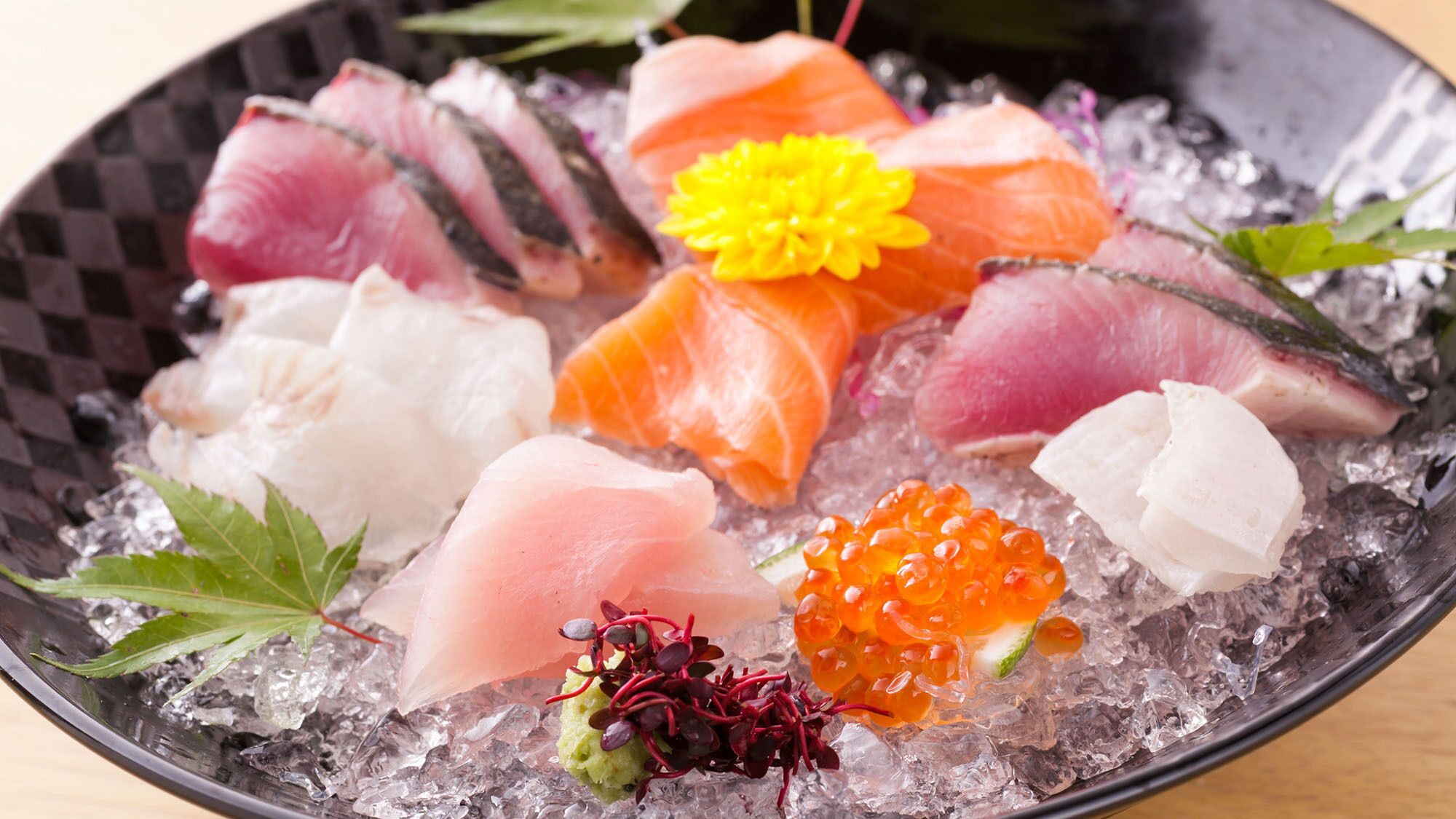 A bowl of sashimi with various fish cuts and garnishes on ice.