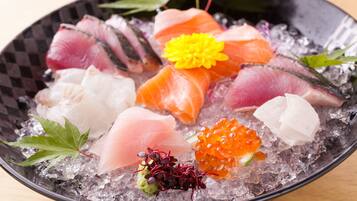 A bowl of sashimi with various fish cuts and garnishes on ice.