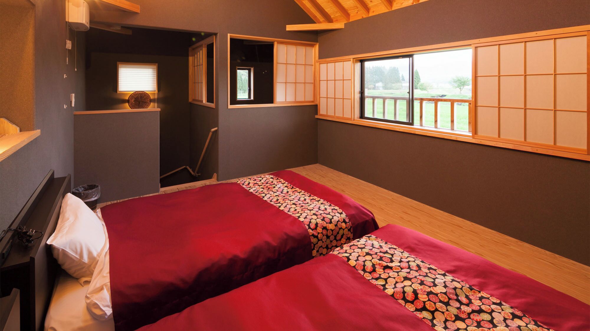 Una habitación con dos camas, un ventanal y un estante pequeño.