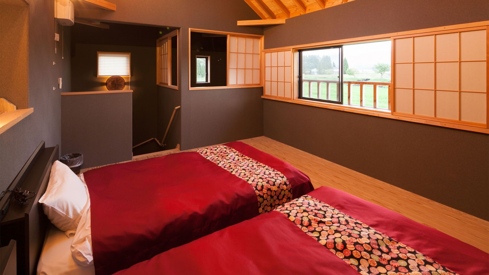 Una habitación con dos camas, una ventana con vistas, un estante pequeño y una puerta que da a otra estancia.
