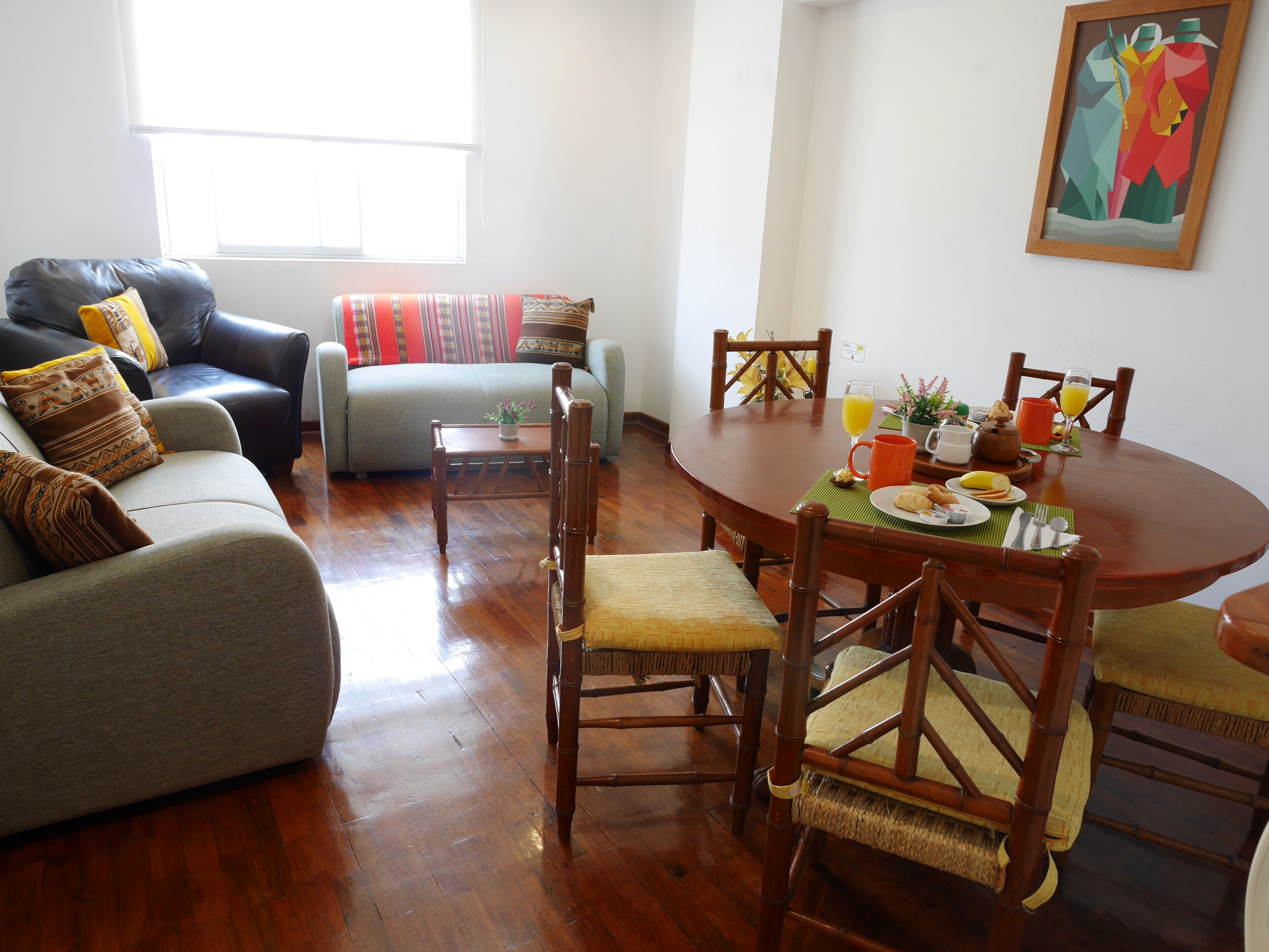Una sala de estar con un sofá, una mesa de comedor con sillas y un cuadro en la pared.