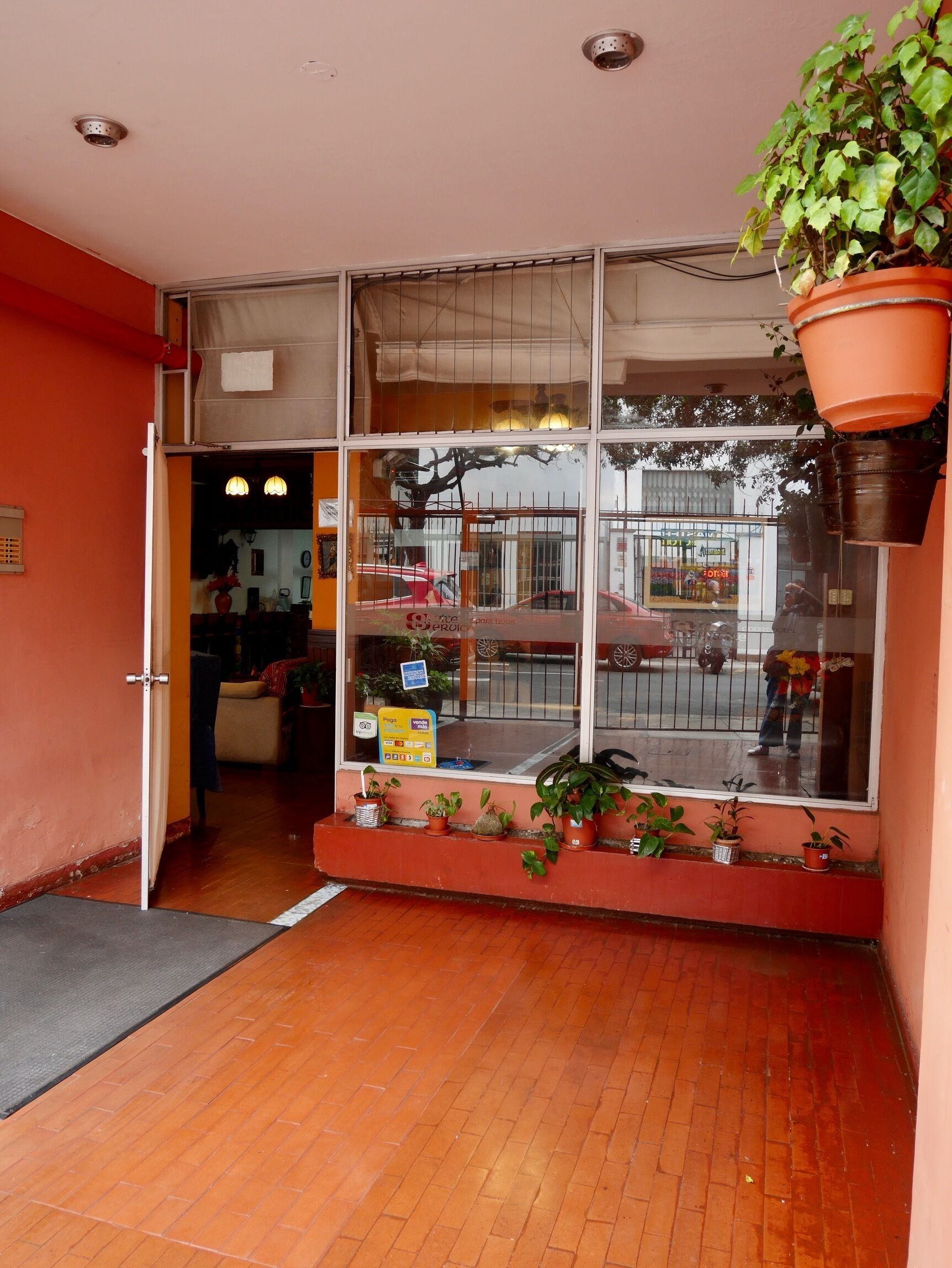 A storefront with a large window, potted plants, and a visible sign for a payment option.