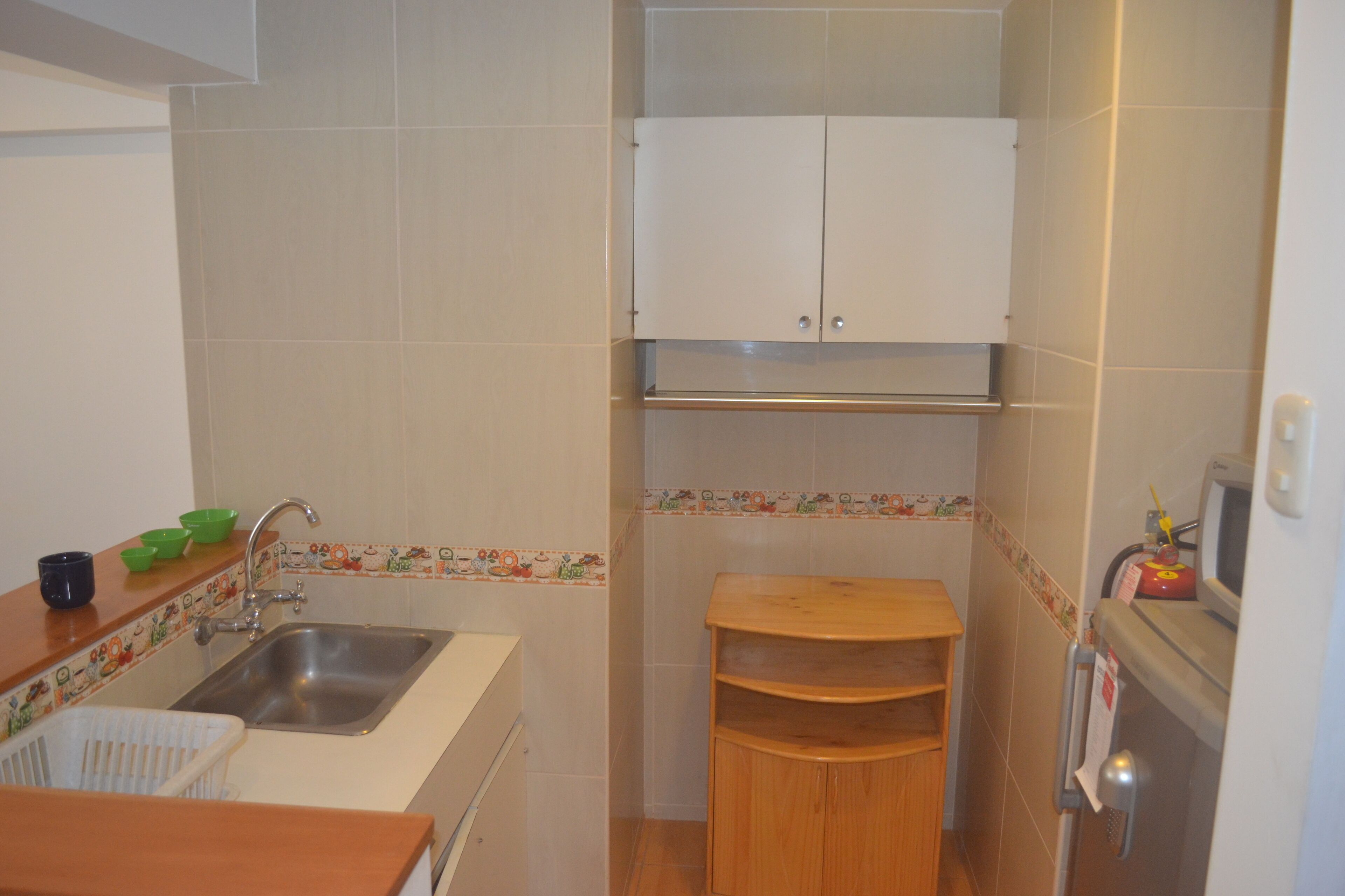 Cocina compacta con lavamanos, armarios y microondas.