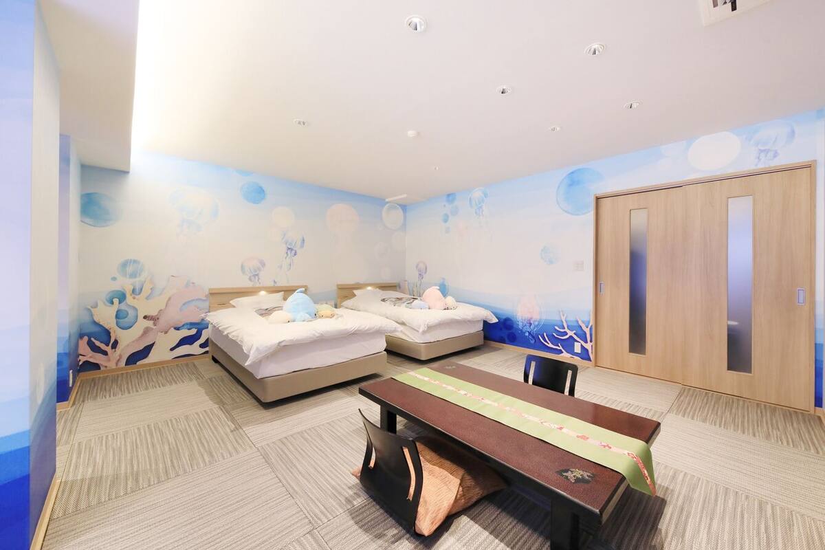 A hotel room with two beds, a desk, and a wardrobe.