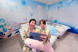 A room with a bed, a wall mural, and a person holding a smartphone. - Yuyado Mikan No Ki (Atami)