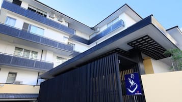 Um edifício moderno com telhado plano, várias varandas e portão de acesso.