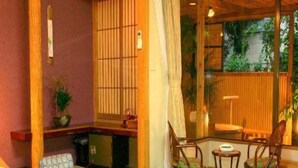Una habitación tradicional japonesa con suelo de tatami, una mesa baja y sillas de madera.