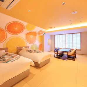 Quarto de hotel com duas camas, uma mesa de jantar com cadeiras e uma janela grande com persianas.
