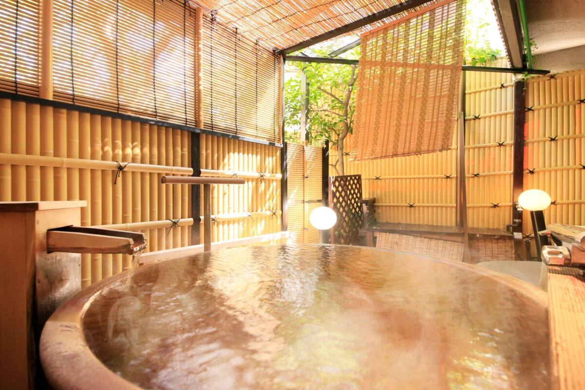 A traditional Japanese onsen with a wooden interior, a hot spring bath, and bamboo walls.