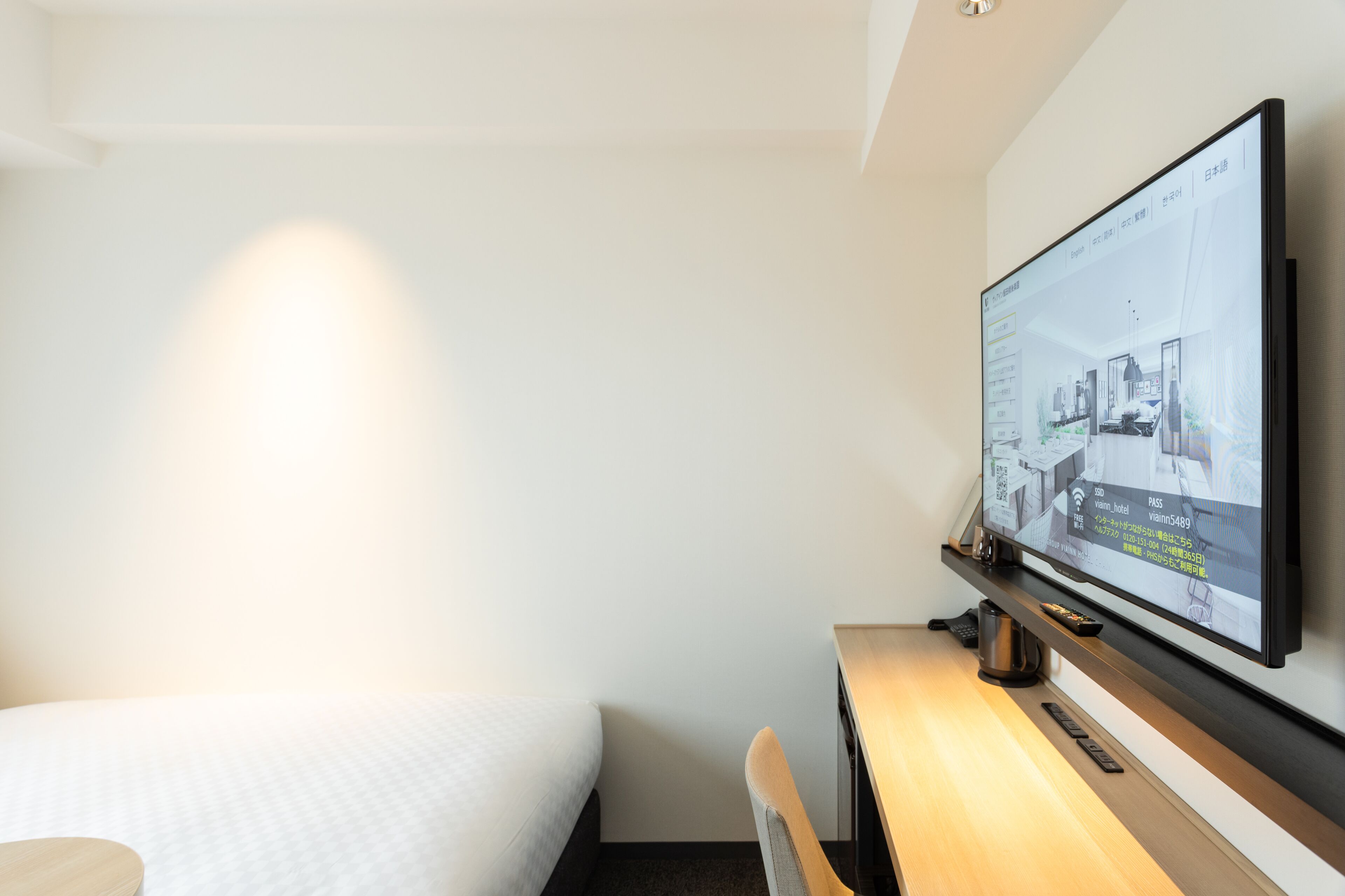 Habitación de hotel con cama, escritorio y televisor de pantalla plana en la pared que muestra un plano de la habitación.