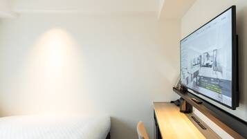 Habitación de hotel con cama, escritorio y televisor de pantalla plana en la pared que muestra un plano de la habitación.
