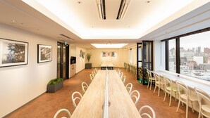 A conference room with a long table, chairs, framed pictures on the walls, and a city view through large windows. - JR WEST GROUP VIA INN Iidabashi Korakuen (Tokyo)