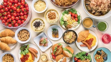 A variety of dishes including a large bowl of cherry tomatoes, several plates with different foods, and a cup of coffee.