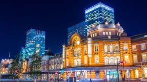 A historic building with classical architecture, a modern glass skyscraper in the background, and a well-lit street scene. - JR WEST GROUP VIA INN Iidabashi Korakuen (Tokyo)