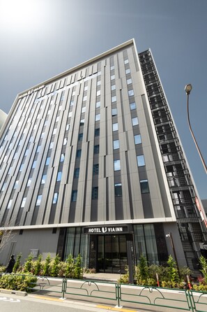 Moderni hotellirakennus, jossa on näyttävä sisäänkäynti, useita kerroksia ja avoin näkymä taivaalle.