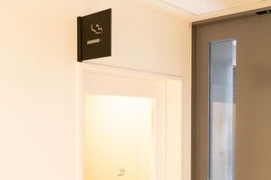 A hotel room entrance with a door, a wall-mounted sign, and a window with a striped pattern.