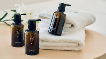 Three bottles of UVA Inn products, a folded white towel, and a white flower on a wooden surface.