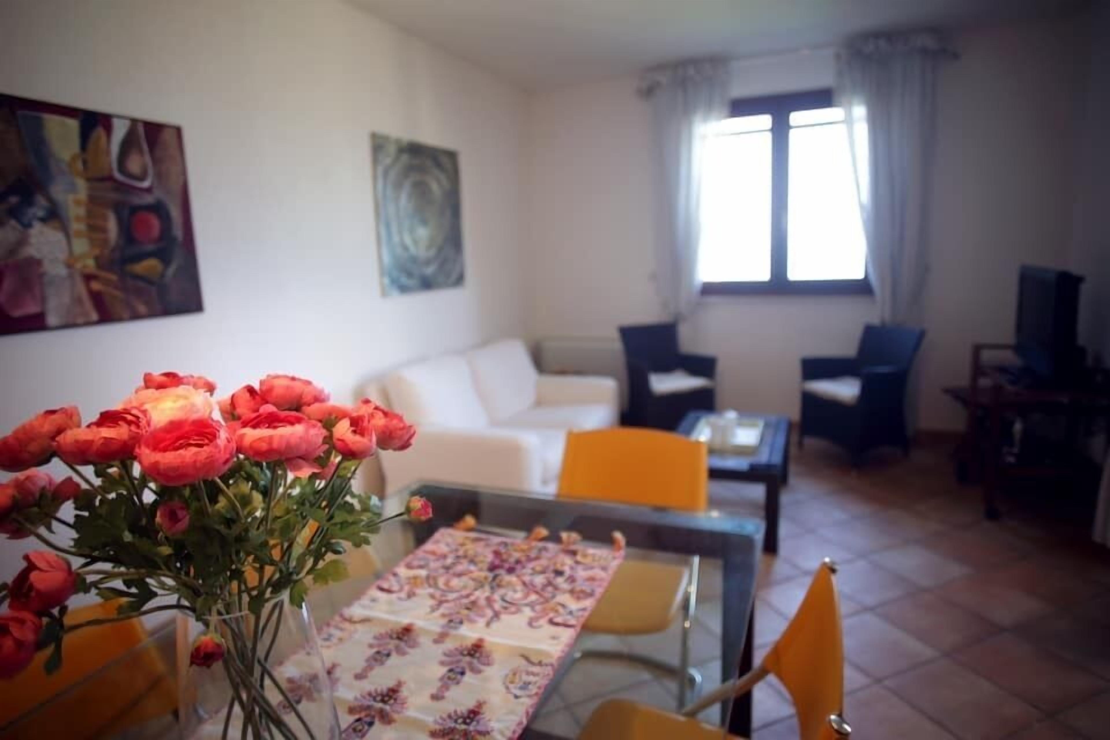 Een woonkamer met een eettafel, stoelen, een bank en een televisie.