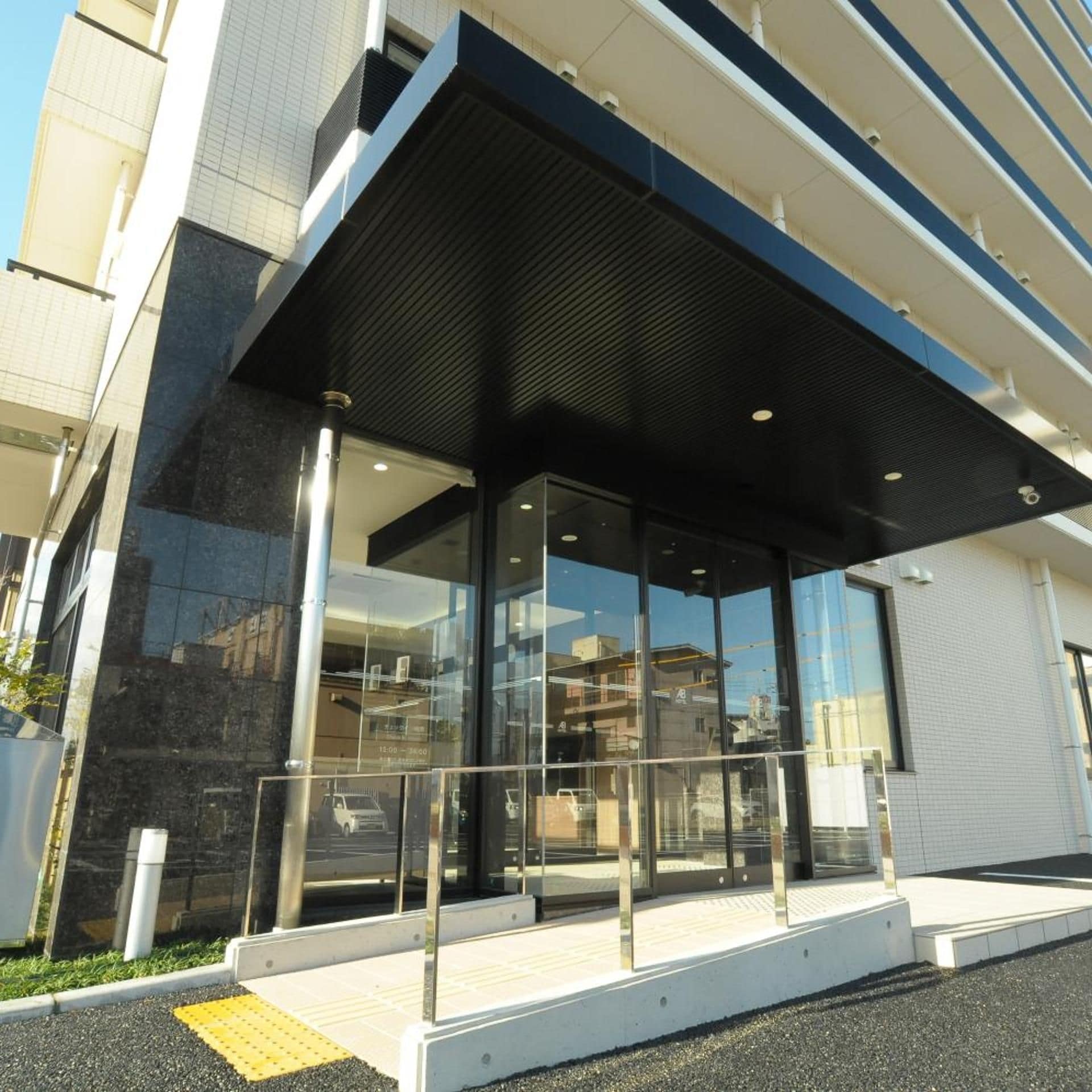 A modern building with a glass entrance and a covered waiting area.