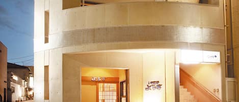 Un edificio de dos pisos con una entrada visible y una escalera que lleva a un piso superior.