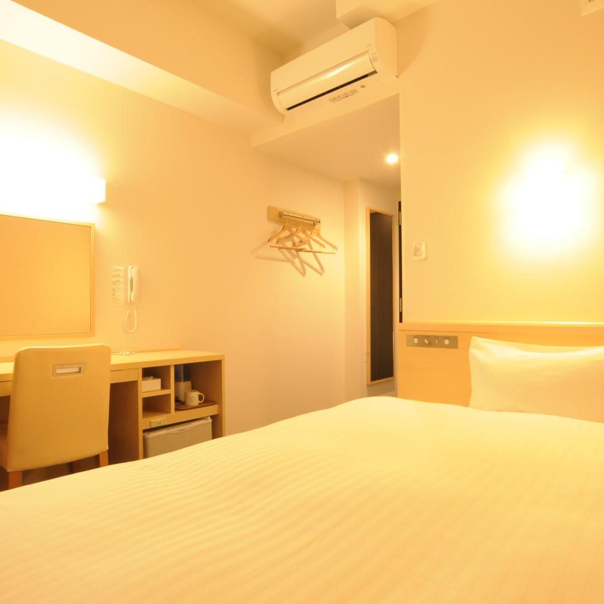 Une chambre d’hôtel équipée d’un lit, d’un bureau, d’une chaise, d’une armoire et d’un appareil de climatisation.