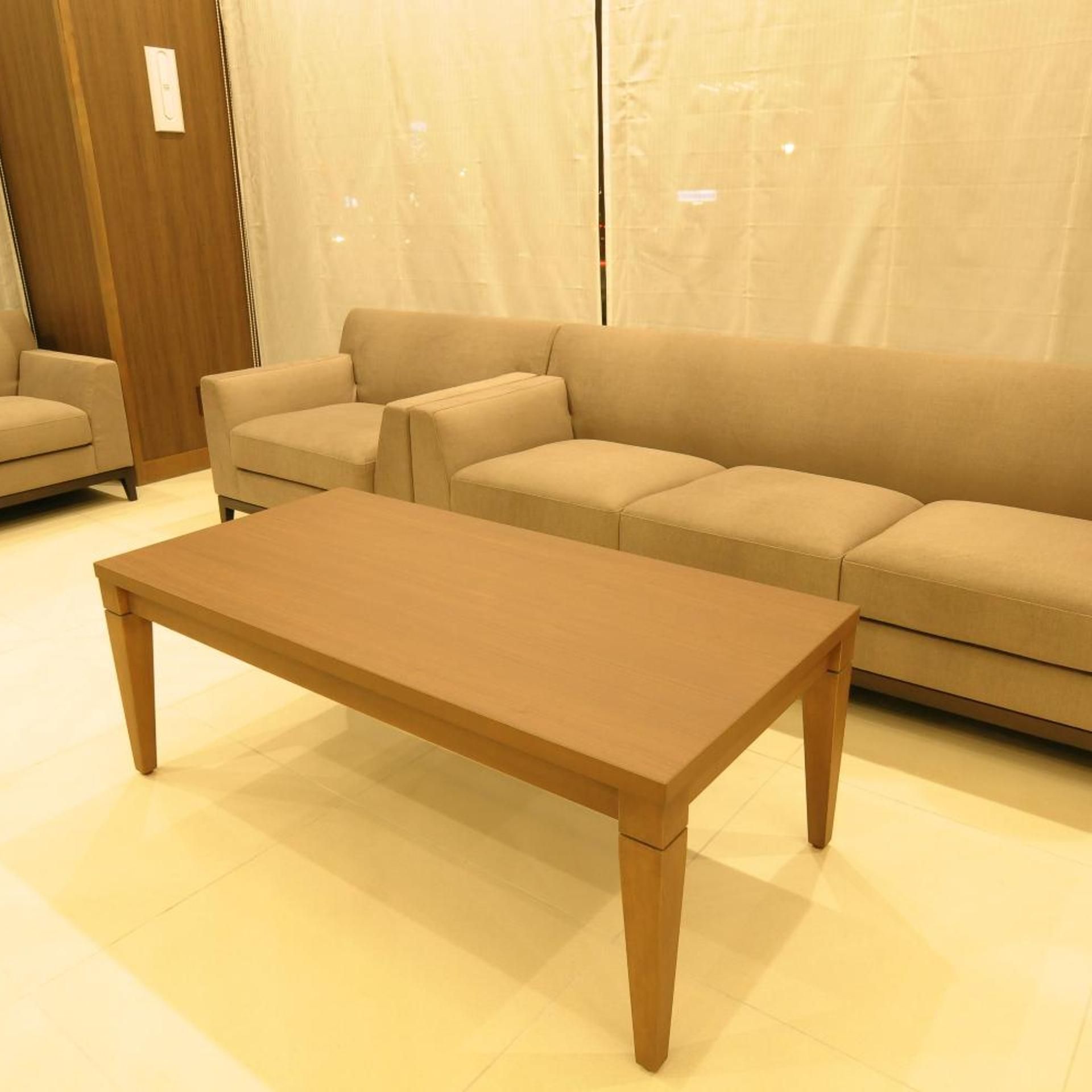 A modern living room with a wooden coffee table, beige sofas, and a wooden floor.