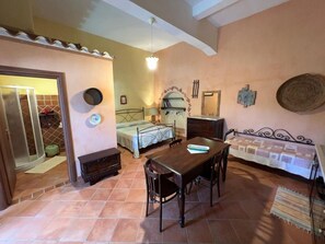 A room with a dining table, chairs, a sofa, a fireplace, and a bed. - B&B Rita and Family (Loceri)