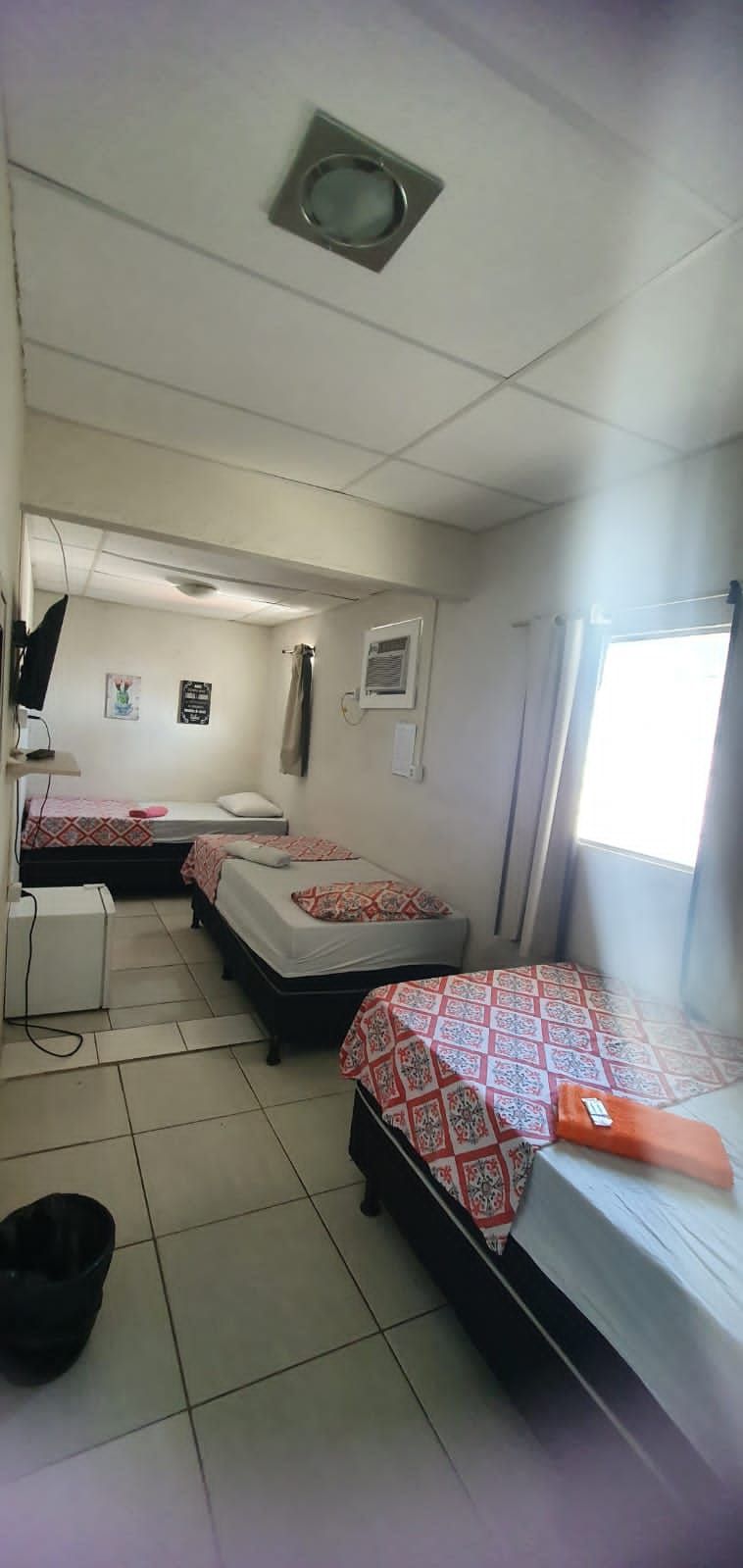 A room with three beds, a desk, a chair, and a window.