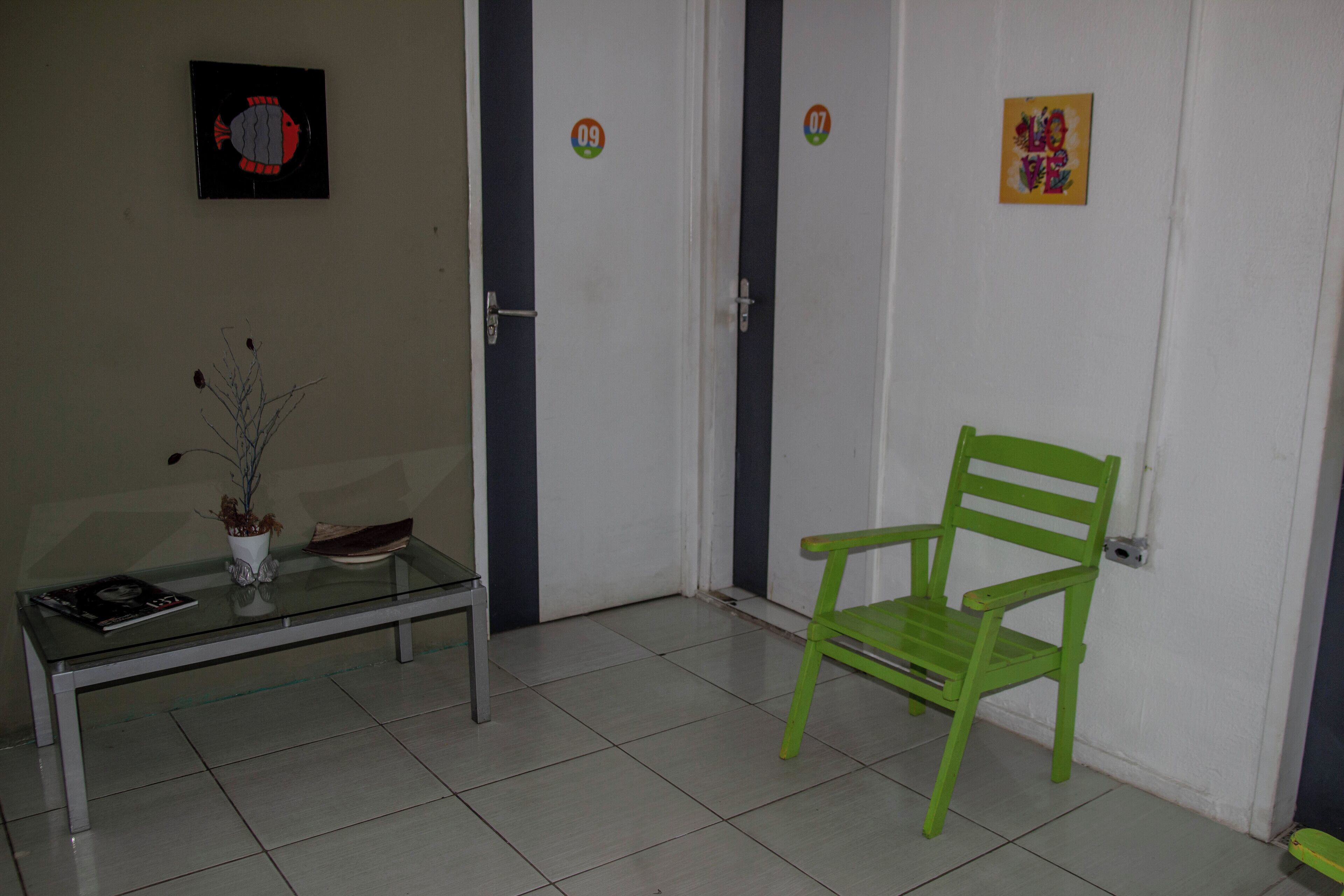 Una habitación con una mesa de vidrio, una silla verde y una puerta con una etiqueta numérica.