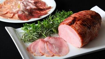 Une assiette avec des tranches de jambon et un jambon entier, sur l’os.