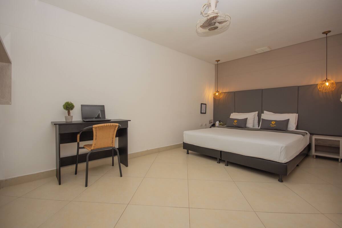 Quarto com uma cama, uma escrivaninha com computador e uma cadeira.