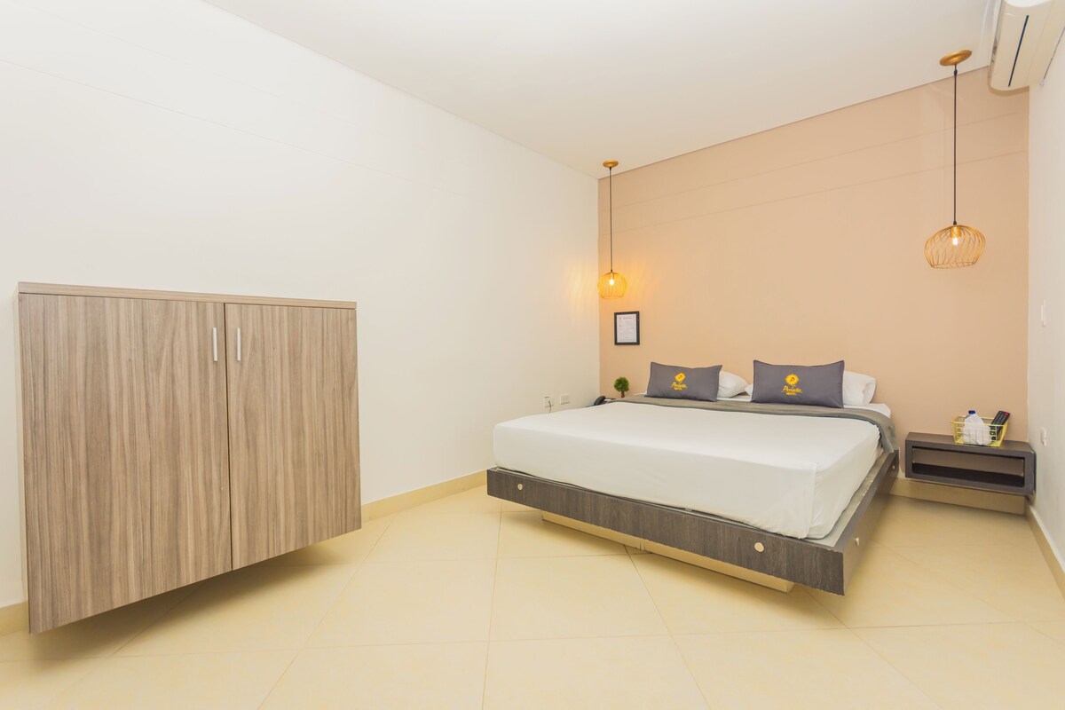 Un dormitorio moderno con cama, armario, mesita de noche y lámpara colgante.