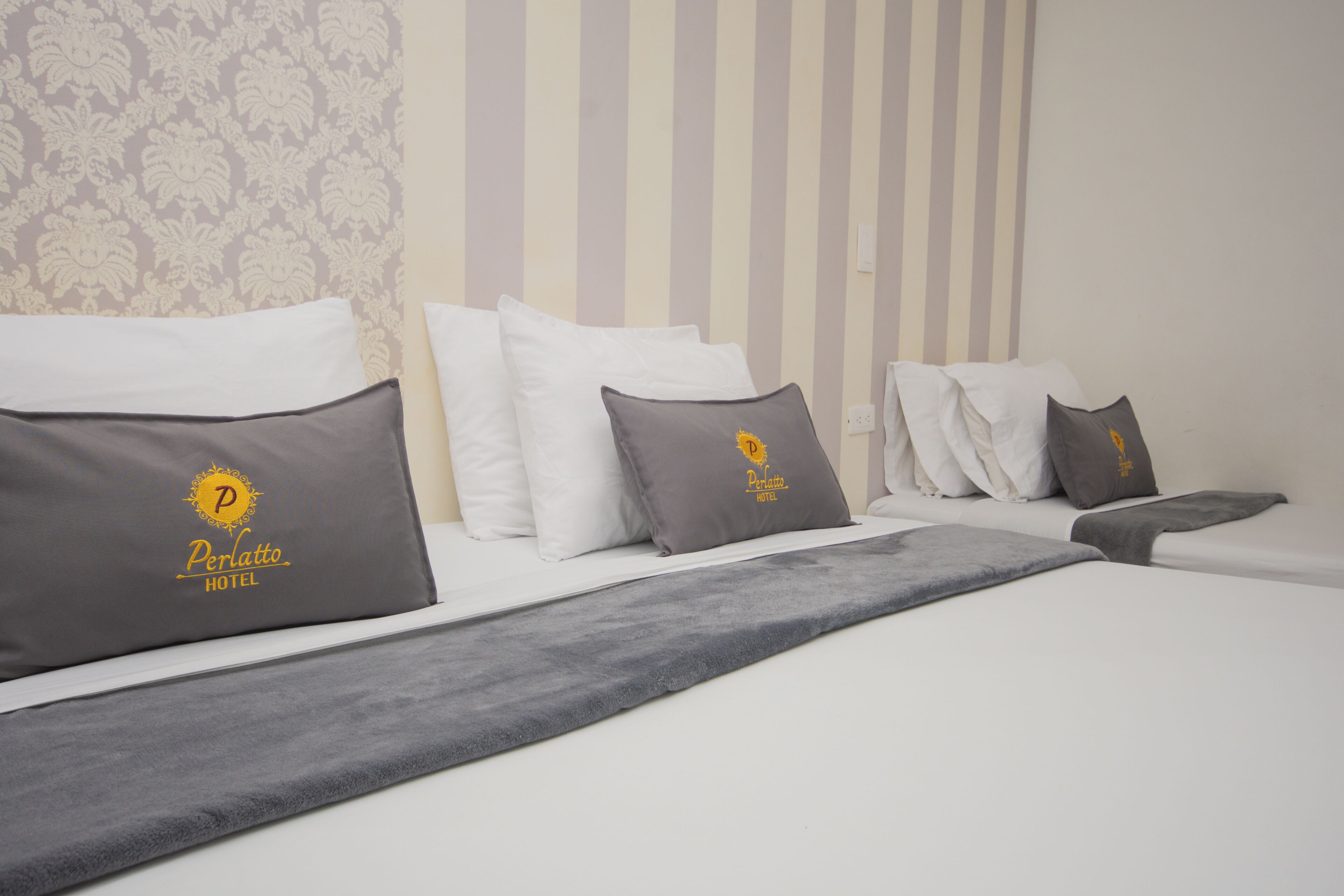 A hotel room with a bed, pillows, and a blanket.