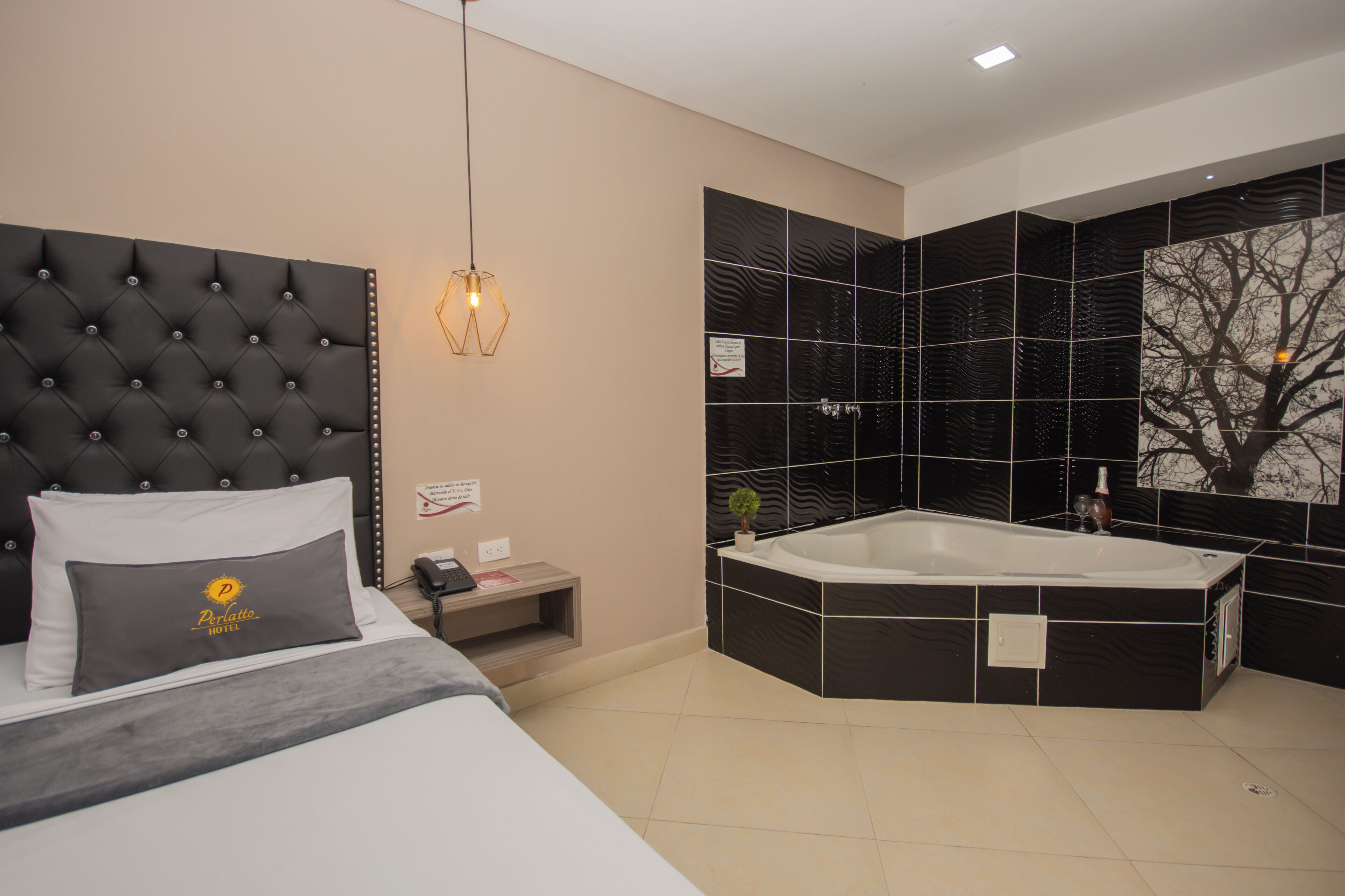 A modern hotel room with a large bed, a separate bathroom with a large bathtub, and a wall-mounted sink.