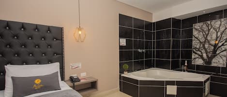 A modern hotel room with a large bed, a separate bathroom with a large bathtub, and a wall-mounted sink.