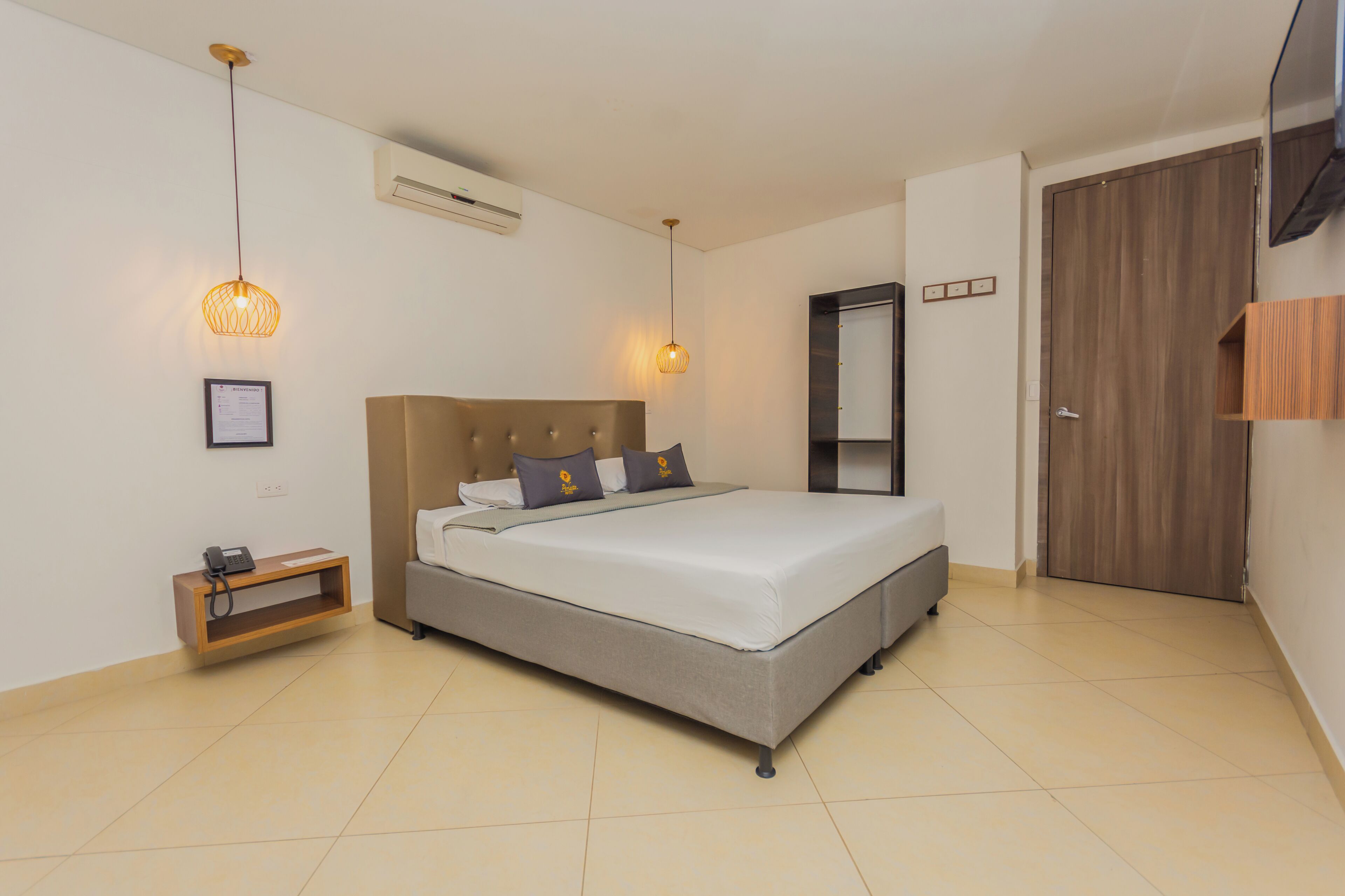 Un dormitorio con cama, mesita de noche, lámpara y una puerta de madera.