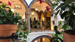 Un atrium à plusieurs niveaux, agrémenté de jardinières en terre cuite, de plafonds en arc de cercle et de luminaires suspendus.