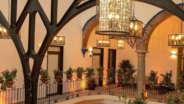 Un atrium intérieur doté d’un escalier central, de plantes en pot et d’un luminaire suspendu.