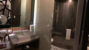 A modern bathroom with a large sink, mirror, and shower area.