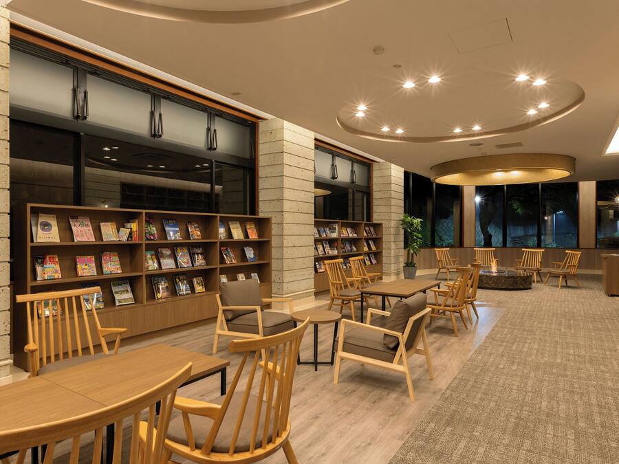 A library with wooden bookshelves, tables, and chairs.