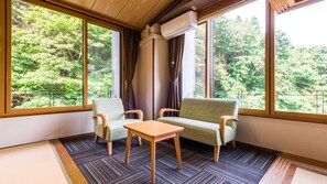 Relax in a serene space with a large window offering views of lush greenery, a comfortable seating area, and climate control.