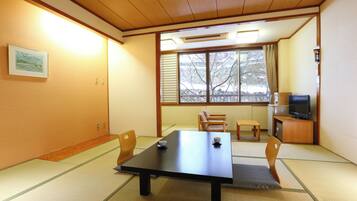 A traditional Japanese room with tatami flooring, a low table, and a television on a wooden cabinet.