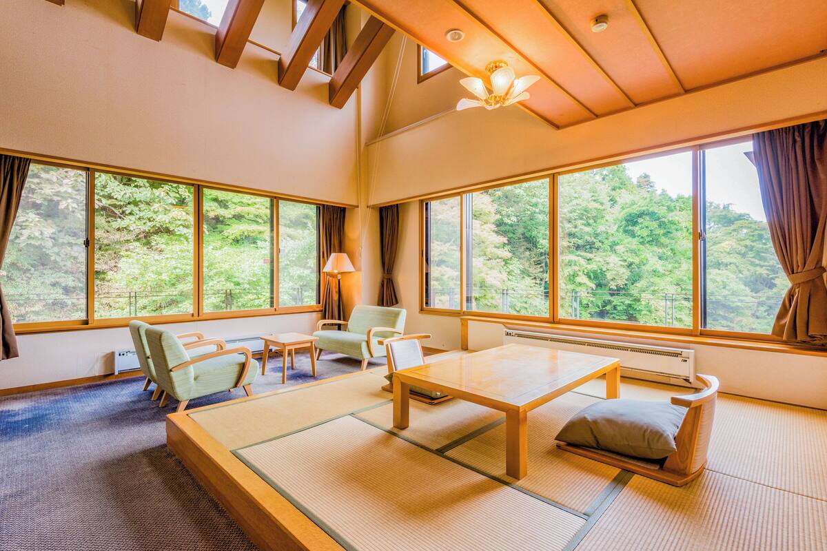 A traditional Japanese-style room with tatami flooring, a low table, and seating.
